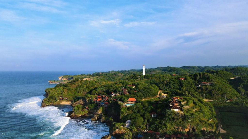 A stunning aerial view of the lush coastline in Bantul, Jogja, Indonesia, featuring vivid green hills and expansive sea.